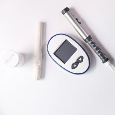 A eagle-view of glucometer, insulin pen and caps for diabetes treatment.