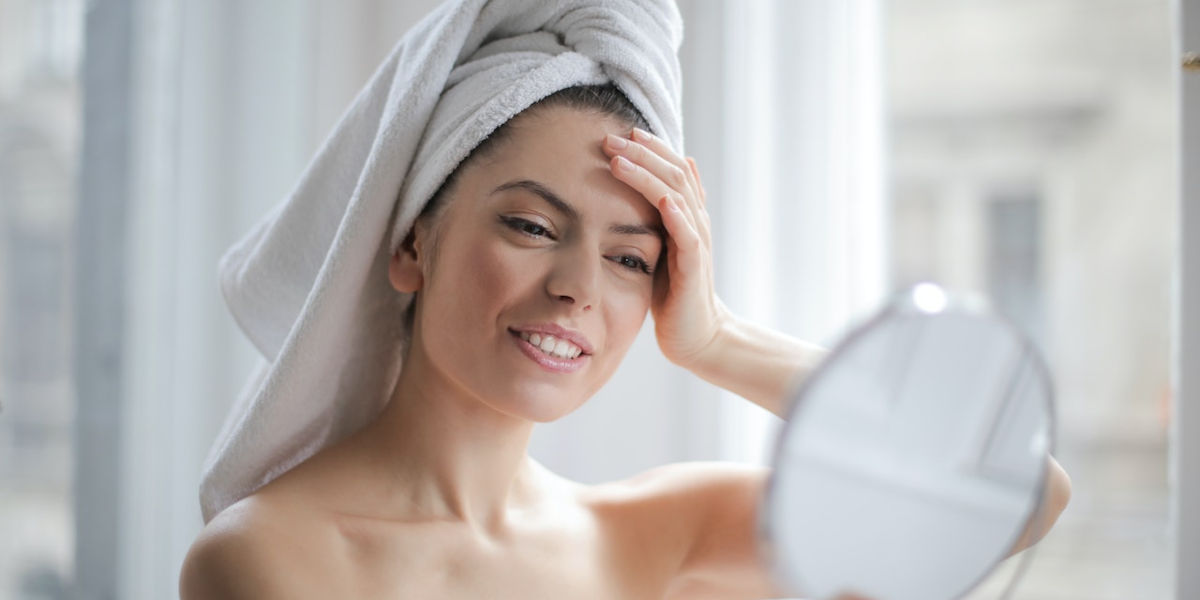 woman looking her face in the mirror